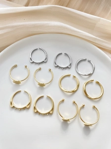 Close-up of a 10-piece gold and silver adjustable ring set on elegant beige silk fabric