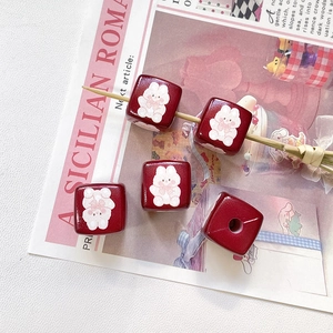 Gros plan de perles carrées rouge foncé avec motifs lapins pour la création de bijoux