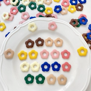 Charmes de fleurs à cinq pétales en résine colorée pour DIY sur une assiette blanche