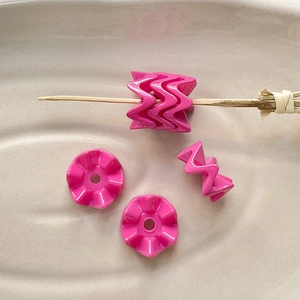 Macro-opname van roze gegolfde acrylkralen voor DIY-sieraden en handgemaakte armbanden