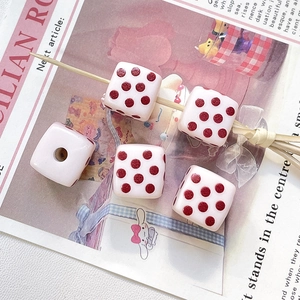 Gros plan de cinq perles de dés en résine rose avec points rouges pour bijoux DIY