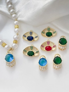 Macro detail of gold-plated evil eye charms with colorful zircons on white silk