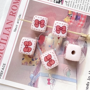 Détail de perles carrées roses avec motif nœud rouge pour bijoux et artisanat DIY