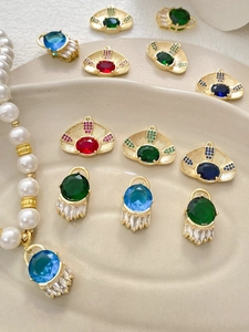 Close-up of gold-plated evil eye charms with colorful zircon stones on ceramic tray