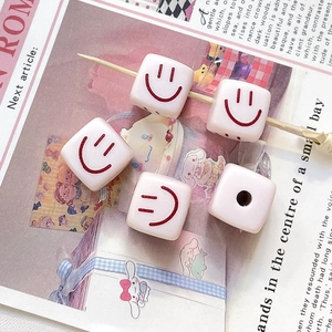 Gros plan de jolies perles carrées crème avec sourire rouge pour bijoux faits main