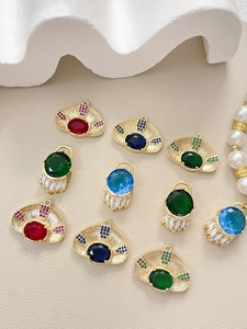 Detailed view of fan-shaped and arched gold-plated evil eye charms with vibrant zircons