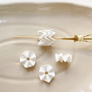 Macro-opname van gegolfde acrylkralen voor DIY-sieraden op een keramische schaal