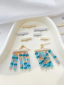 Détail des connecteurs en or 14 carats et boucles d'oreilles pompons aux perles colorées