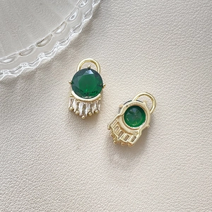 Detail of gold-plated evil eye charms with green crystals and baguette zircon insets