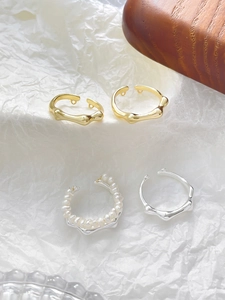 Detailansicht unregelmäßiger Ringe mit Textur und Perlen auf weißem Hintergrund
