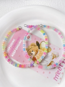 Detail of candy-colored translucent resin beads with silver metal clasps in a white bowl