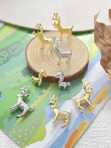 Dettaglio dei ciondoli cervo placcati oro 14k con trama martellata su base in legno