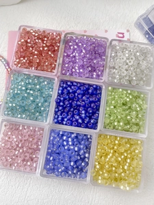 Detailed view of 3mm frosted cat-eye glass seed beads in 9 candy colors organized in boxes