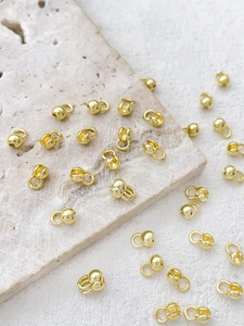 Macro view of 14k gold-plated jewelry bead tips and crimp covers for DIY necklaces