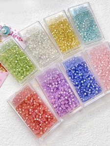 Close-up of 8 colors of 3mm cat eye glass beads stored in individual clear plastic boxes