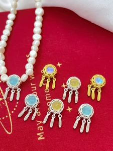 Detailed view of dreamcatcher charms in gold and silver plating with colorful gemstones