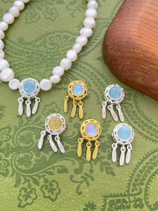 Detail of dreamcatcher charms with feathers and gemstones on a pearl necklace