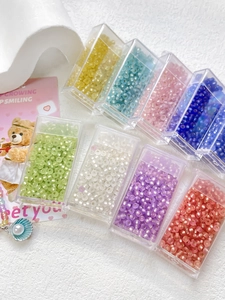 Macro detail of 8-color 3mm glass cat-eye beads organized in a transparent storage box