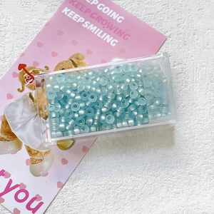 Detail view of light blue frosted 3mm glass seed beads in a clear plastic storage box