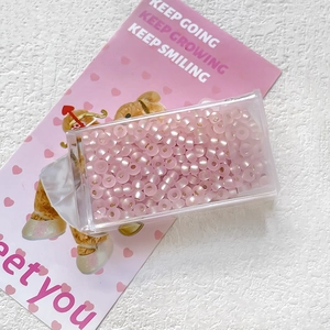Detail of matte pink cat-eye glass beads for DIY jewelry in a clear storage case