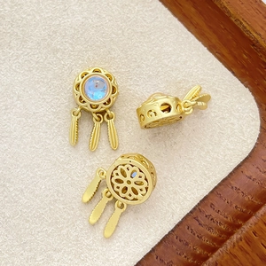 Detailed close-up of golden dreamcatcher charms with feathers and blue gemstone inlay