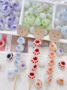 Macro shot of colorful cat paw beads and wooden bear charms for DIY jewelry making