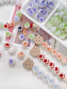 Close-up of colorful resin cat paw beads and wooden bear beads for DIY jewelry making