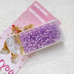 Close-up of 3mm purple cat-eye glass beads in a storage box for DIY jewelry making