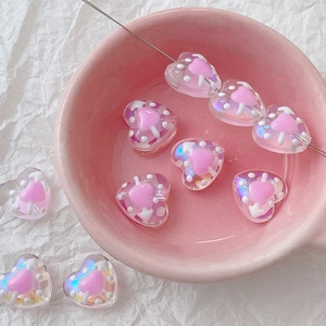 Macro view of iridescent pink heart beads and a crafting needle in a pink bowl