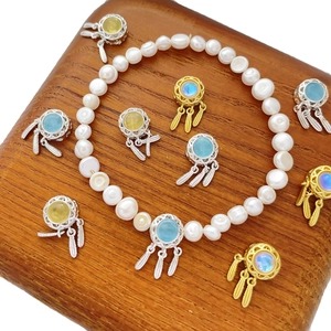 Freshwater pearl bracelet featuring silver and gold dreamcatcher charms with colorful gemstones