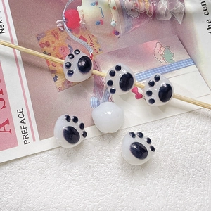 Detailed macro view of black and white cat paw shaped ceramic beads on a wooden stick