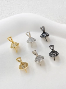Dettaglio dei ciondoli a forma di abito da balletto in oro e argento con zirconi micro pavé