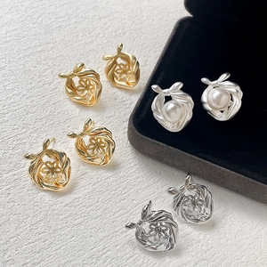 Orecchini a fiocco in oro e argento con perle su sfondo bianco strutturato
