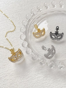 Dettaglio di ciondoli maschera veneziana in oro argento e nero con pietre di zircone