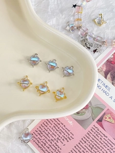 Detailed view of heart-shaped planet charms in gold and silver plating on ceramic tray
