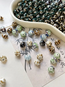 Detailed view of assorted glazed ceramic lantern and pumpkin beads for DIY jewelry making