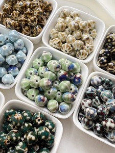Detailed macro view of assorted glazed ceramic lantern beads in a white porcelain dish