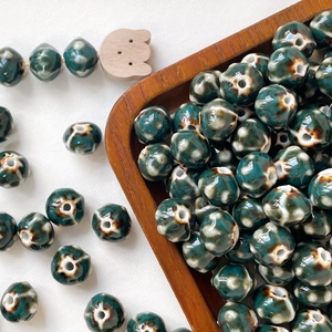 Detail of dark green glazed ceramic pumpkin beads on wooden tray for DIY jewelry making