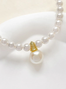 Dettaglio del ciondolo placcato oro 18k con perla su un'elegante collana di perle bianche