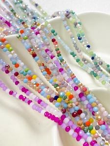 Gros plan de perles en verre facettées colorées pour bijoux DIY dans un plat en céramique