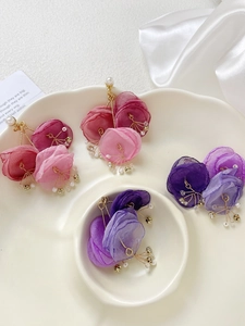 Detail of mesh crystal flower earrings in pink and purple colors on a ceramic tray