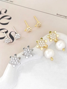 Detail of snowflake zircon earrings with gold plating and elegant pearl pendants