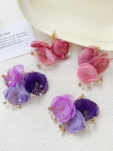 Detail of handmade mesh fabric flower earrings with pearls and golden stamen accents