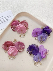 Detailed macro view of pink and purple mesh flower charms with pearls for DIY earring making