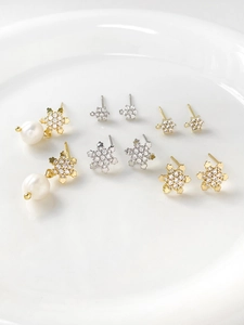 Detailed close-up of gold and silver snowflake earrings with sparkling cubic zirconia in a dish