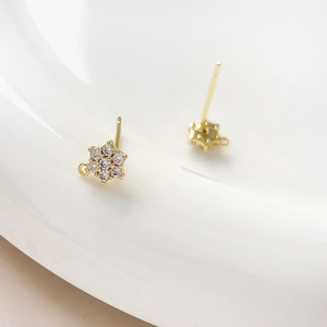 Macro detail of gold plated flower earring stud with zircon stones and a small hanging loop