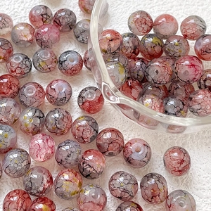 Vista macro di perle in vetro 10mm rosa e grigie con foglia d'oro per gioielli DIY