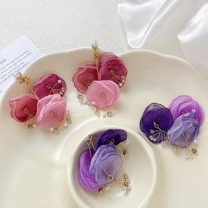 Elegant chiffon flower drop earrings with pearls and crystals on a white ceramic plate