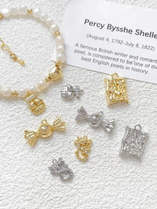 Macro detail of 18k gold plated dragon and candy charms with cubic zirconia on white surface