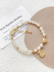 Detail view of 18k gold plated pearl bracelet with heart and zircon charms on soft texture